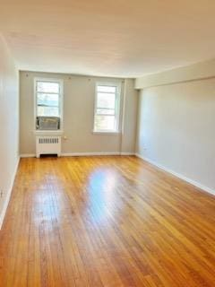 empty room with light hardwood / wood-style floors, plenty of natural light, and radiator heating unit