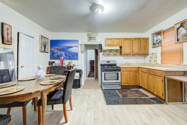 kitchen featuring sink, decorative backsplash, stainless steel gas range, and light hardwood / wood-style flooring