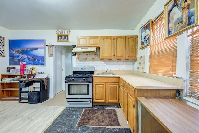 kitchen featuring sink, dark hardwood / wood-style floors, stainless steel gas range, and tasteful backsplash