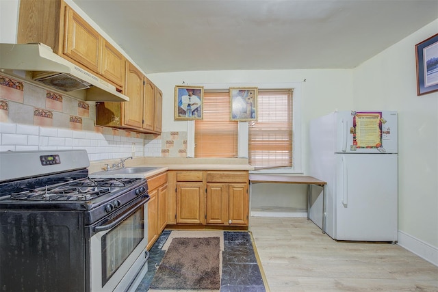 kitchen with white fridge, decorative backsplash, sink, stainless steel range with gas stovetop, and light hardwood / wood-style flooring