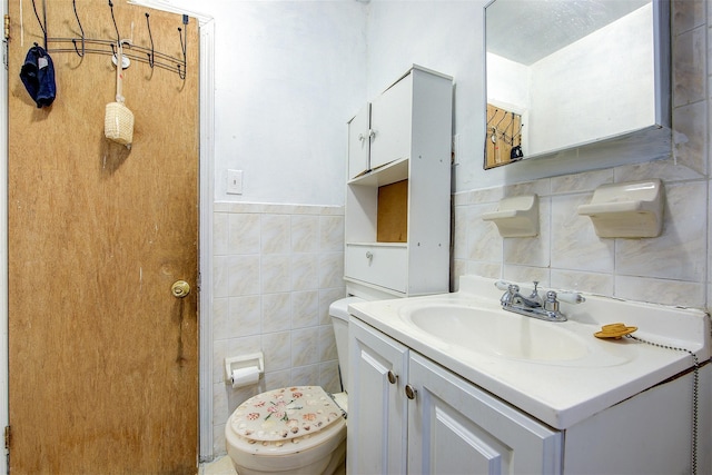 bathroom featuring toilet, vanity, and tile walls