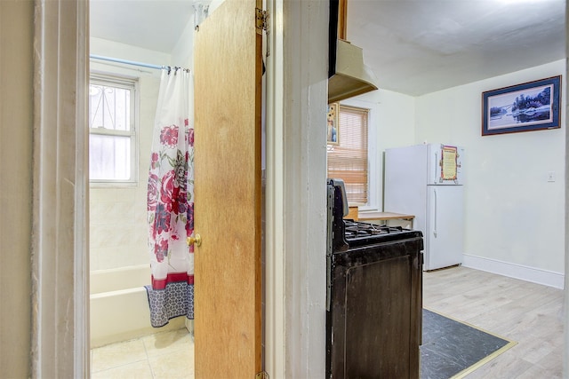 interior space with black gas range, white refrigerator, and light hardwood / wood-style flooring