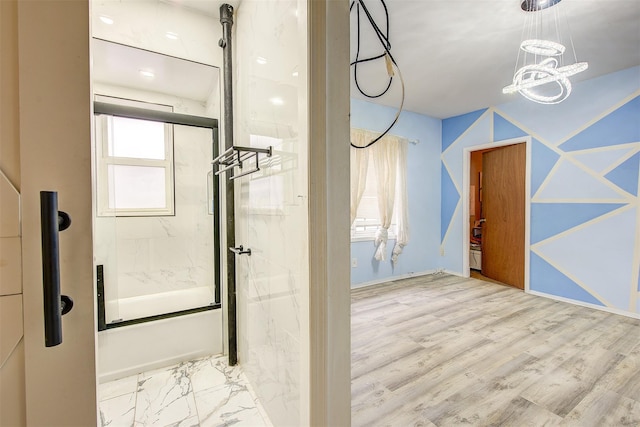 bathroom with combined bath / shower with glass door and an inviting chandelier