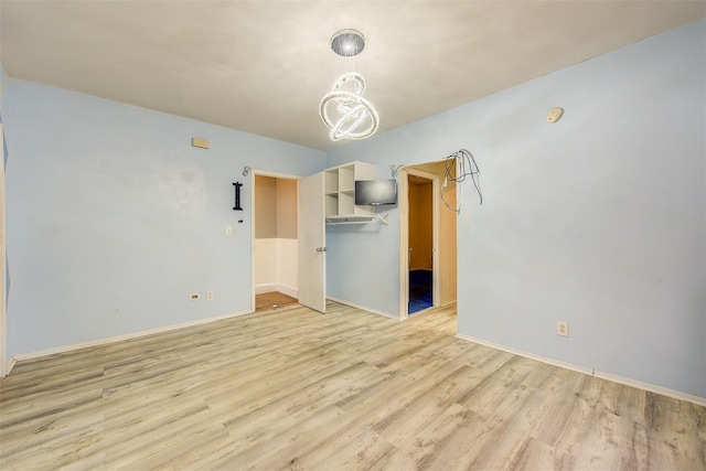 empty room with light hardwood / wood-style floors and a notable chandelier