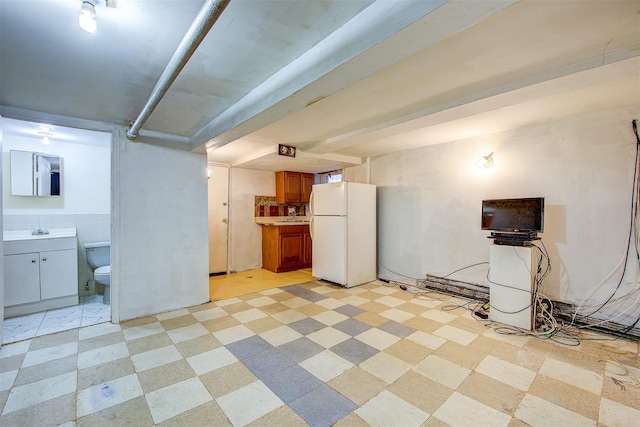 basement with sink and white refrigerator