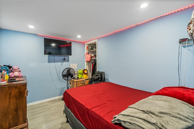 bedroom featuring a walk in closet and light hardwood / wood-style flooring