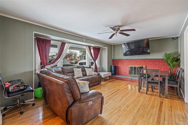 living room with light hardwood / wood-style flooring, crown molding, a fireplace, and ceiling fan