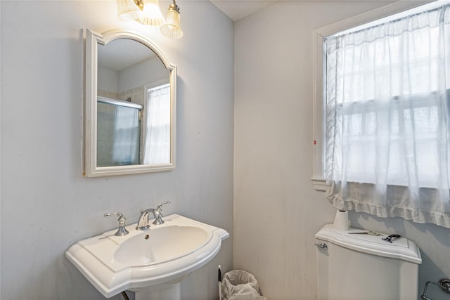 bathroom with sink, a tile shower, and toilet