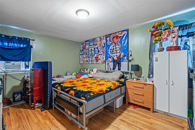 bedroom with cooling unit and light hardwood / wood-style floors