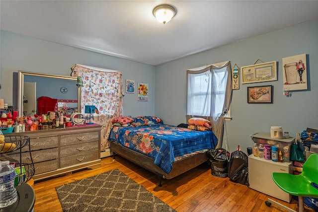 bedroom with hardwood / wood-style flooring and a baseboard heating unit