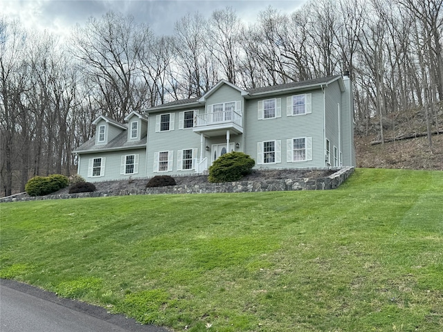 view of front of house featuring a balcony and a front lawn