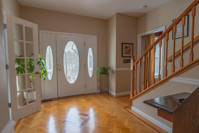 foyer entrance with stairs and baseboards