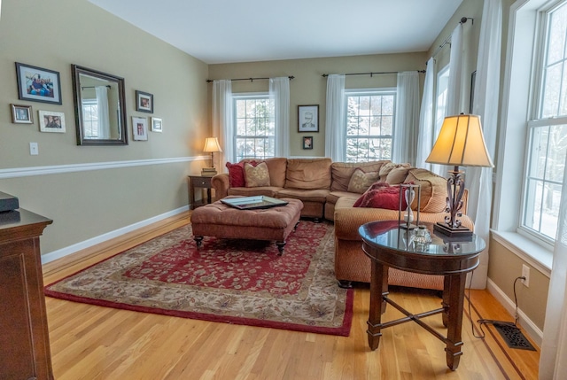 living area featuring visible vents, baseboards, and wood finished floors