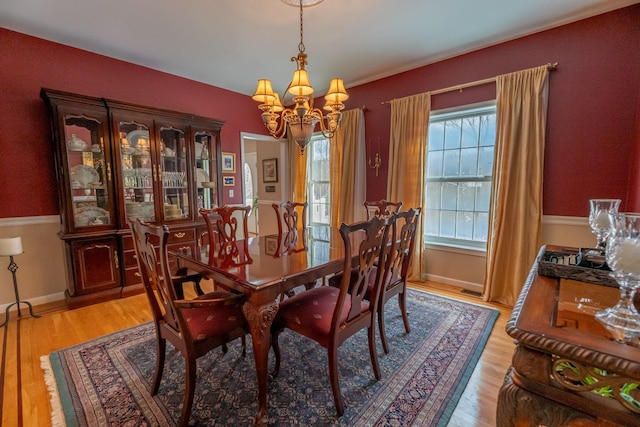 dining room with baseboards, light wood-type flooring, and an inviting chandelier