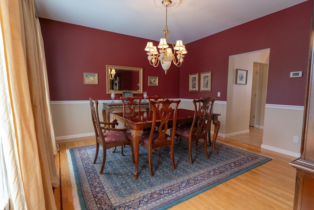 dining room with baseboards, an inviting chandelier, and wood finished floors