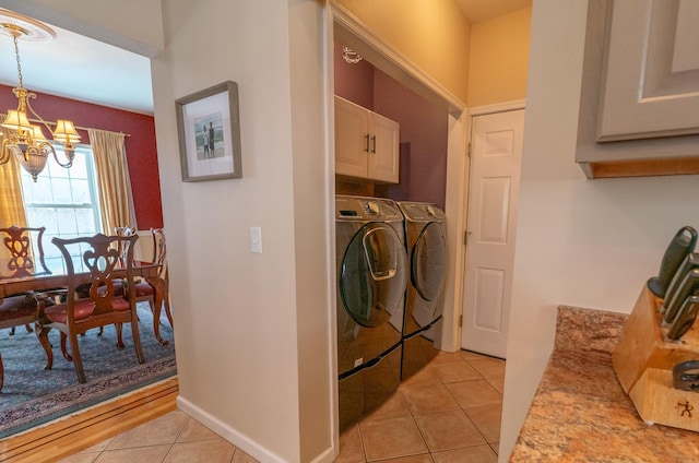 laundry room featuring light tile patterned floors, baseboards, an inviting chandelier, cabinet space, and washing machine and dryer