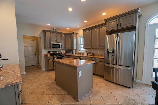 kitchen with gray cabinetry, recessed lighting, appliances with stainless steel finishes, light tile patterned floors, and light stone countertops