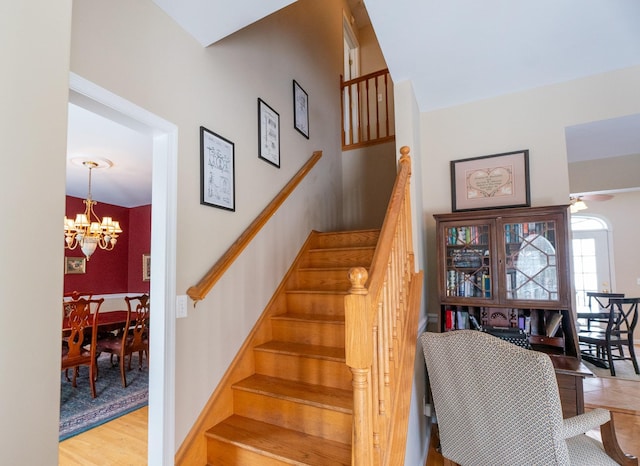 stairs with wood finished floors, baseboards, and a chandelier