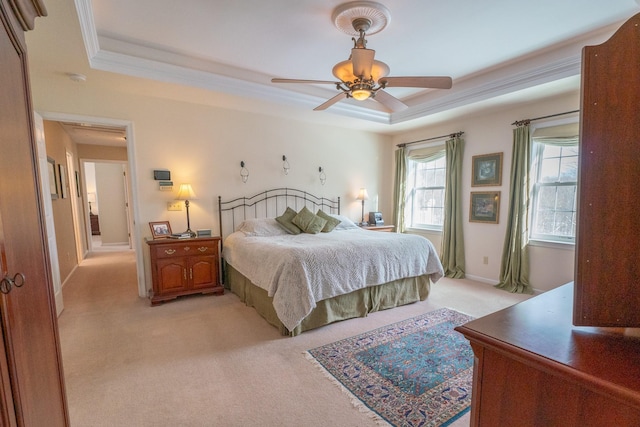 bedroom featuring baseboards, ornamental molding, light carpet, a raised ceiling, and a ceiling fan