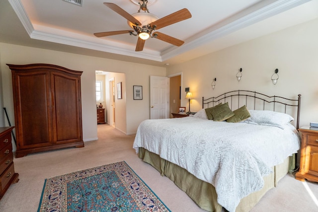 bedroom featuring light carpet, ornamental molding, a ceiling fan, a tray ceiling, and baseboards