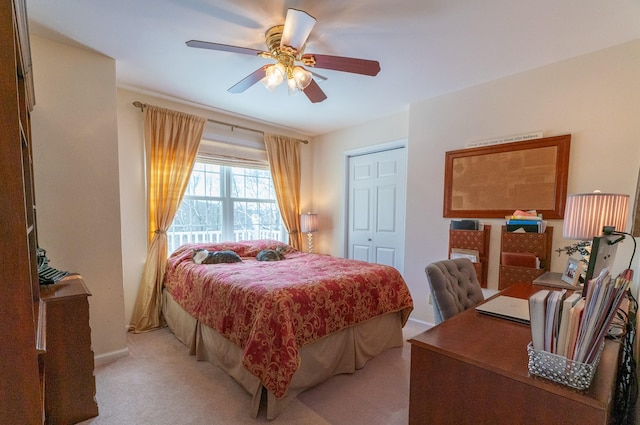 bedroom featuring baseboards, light colored carpet, a closet, and ceiling fan