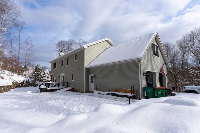 snow covered back of property featuring a garage