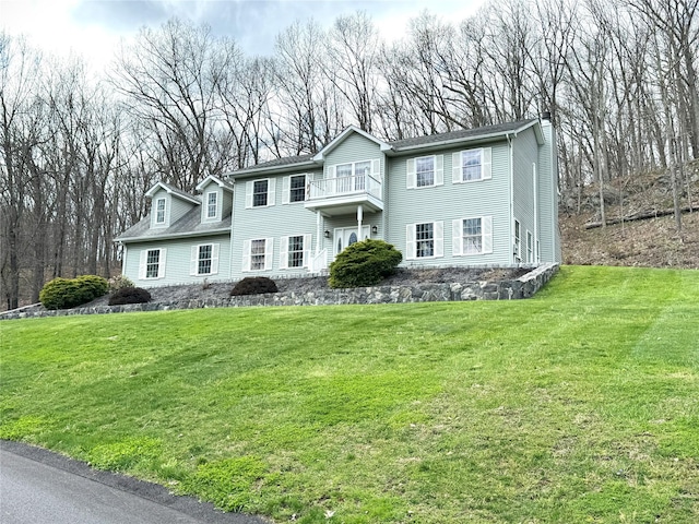 view of front of property featuring a chimney, a front lawn, and a balcony