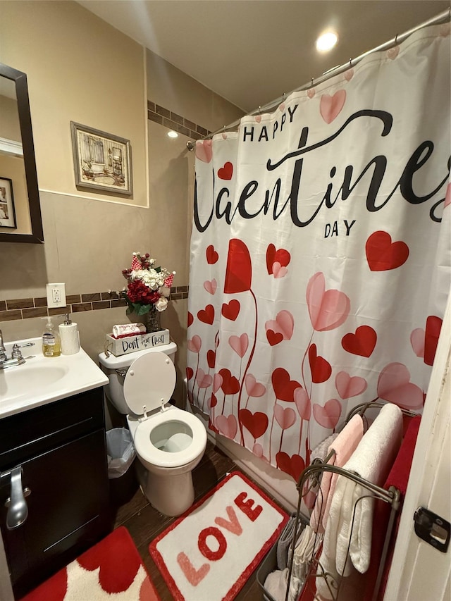 bathroom with toilet, vanity, and tile walls