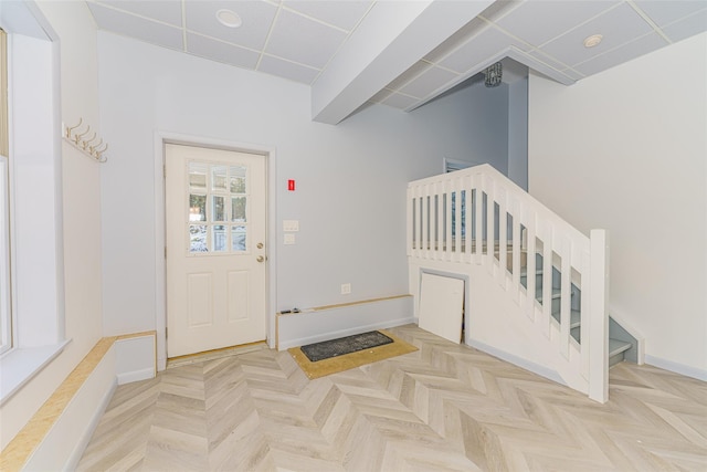 foyer with light parquet floors and a drop ceiling