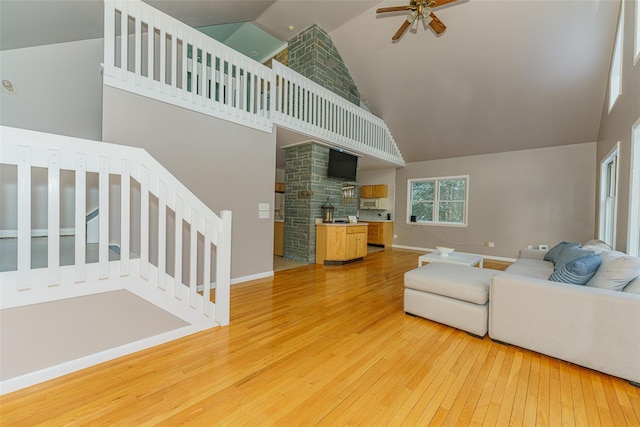 living room with ceiling fan, wood-type flooring, and a towering ceiling