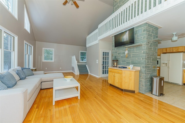 living room featuring light wood-type flooring, ceiling fan, and a high ceiling