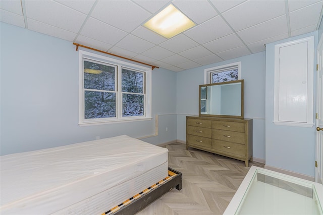 bedroom with light parquet floors and a drop ceiling