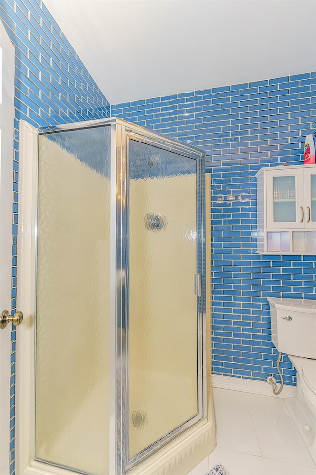 bathroom with a shower with shower door, tile walls, and tile patterned floors