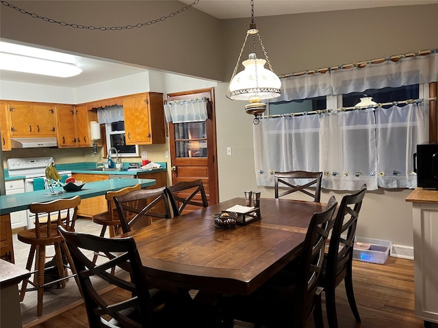 dining area with dark wood-style flooring, baseboards, and a notable chandelier