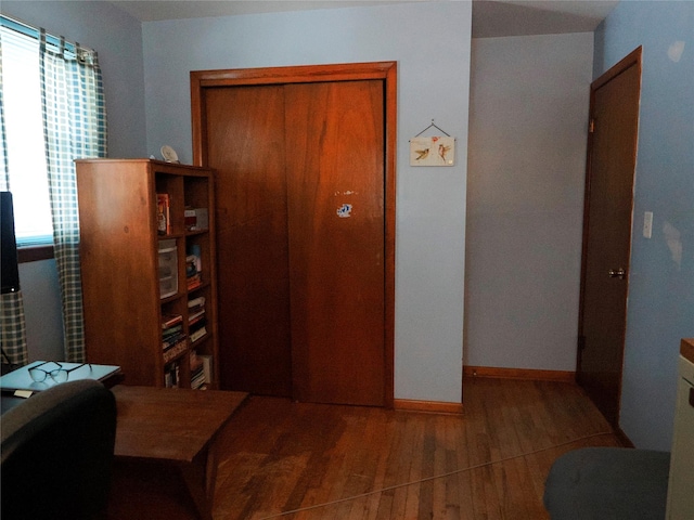 bedroom with a closet, baseboards, and wood finished floors