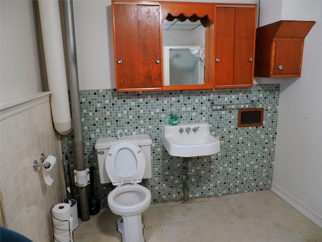 bathroom with tile patterned flooring, a sink, toilet, and tile walls