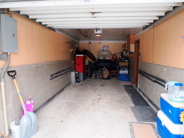 garage featuring concrete block wall, a garage door opener, and electric panel