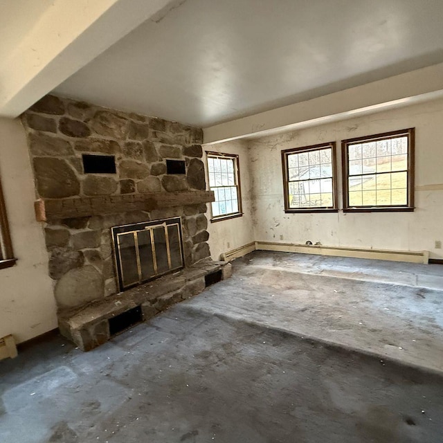 interior space featuring concrete flooring, a stone fireplace, and beamed ceiling