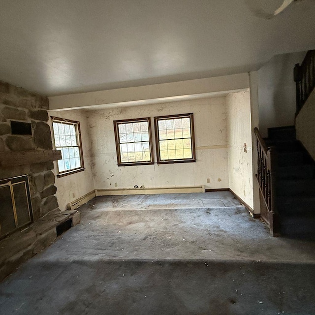 interior space featuring a healthy amount of sunlight, a stone fireplace, and concrete flooring