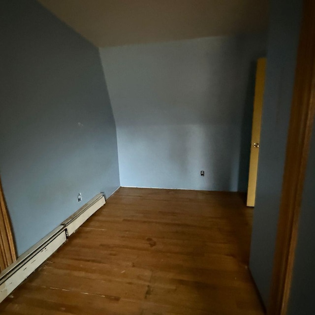 spare room featuring a baseboard heating unit and hardwood / wood-style floors