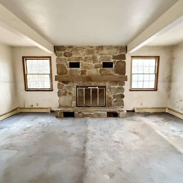 unfurnished living room featuring concrete flooring, a stone fireplace, and a wealth of natural light