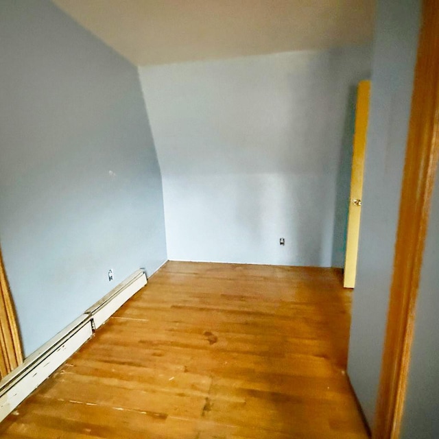 empty room with wood-type flooring and a baseboard heating unit