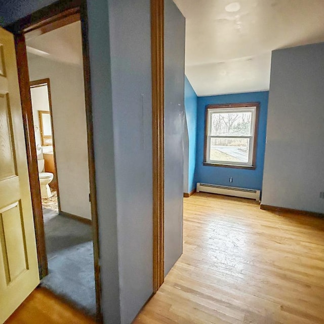 corridor with a baseboard radiator, vaulted ceiling, and light hardwood / wood-style floors