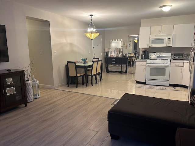 kitchen with hanging light fixtures, white cabinets, white appliances, and light hardwood / wood-style flooring