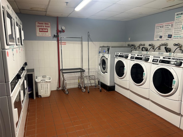 washroom featuring stacked washing maching and dryer, dark tile patterned flooring, and washer and dryer