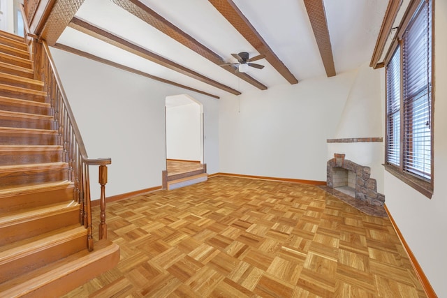 unfurnished living room with light parquet flooring, a large fireplace, ceiling fan, and beam ceiling