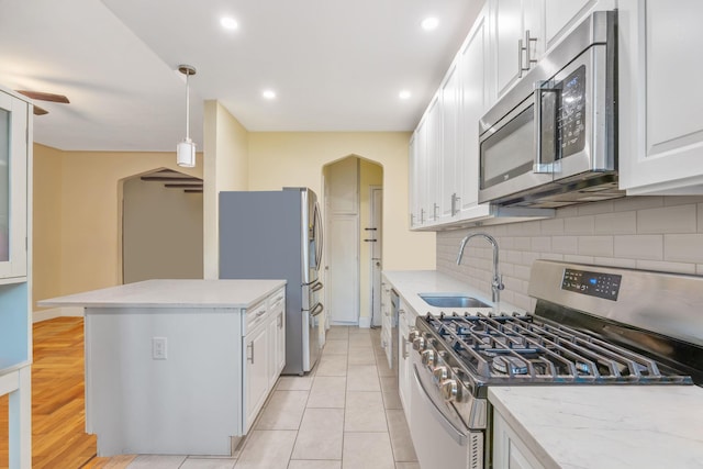 kitchen featuring sink, appliances with stainless steel finishes, white cabinetry, hanging light fixtures, and tasteful backsplash