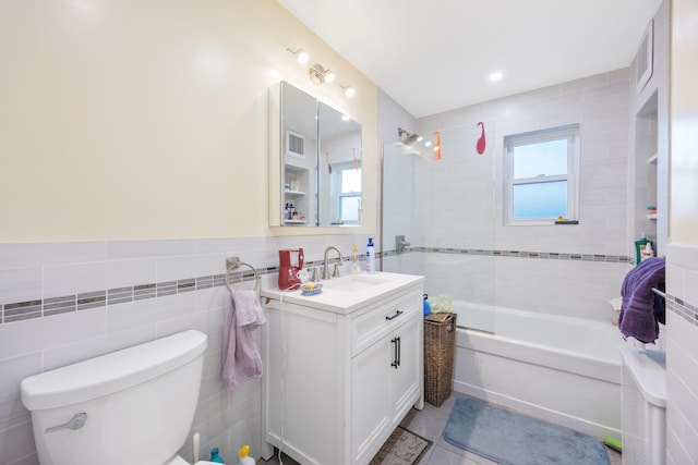 full bathroom with tiled shower / bath, tile walls, tile patterned flooring, vanity, and toilet