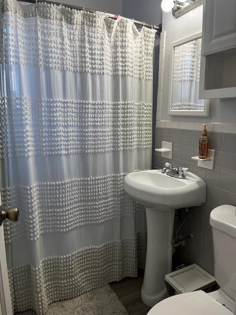 bathroom featuring tile walls and toilet