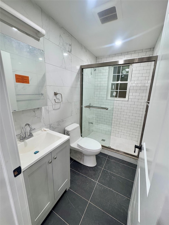 bathroom featuring toilet, tile patterned flooring, tile walls, an enclosed shower, and vanity